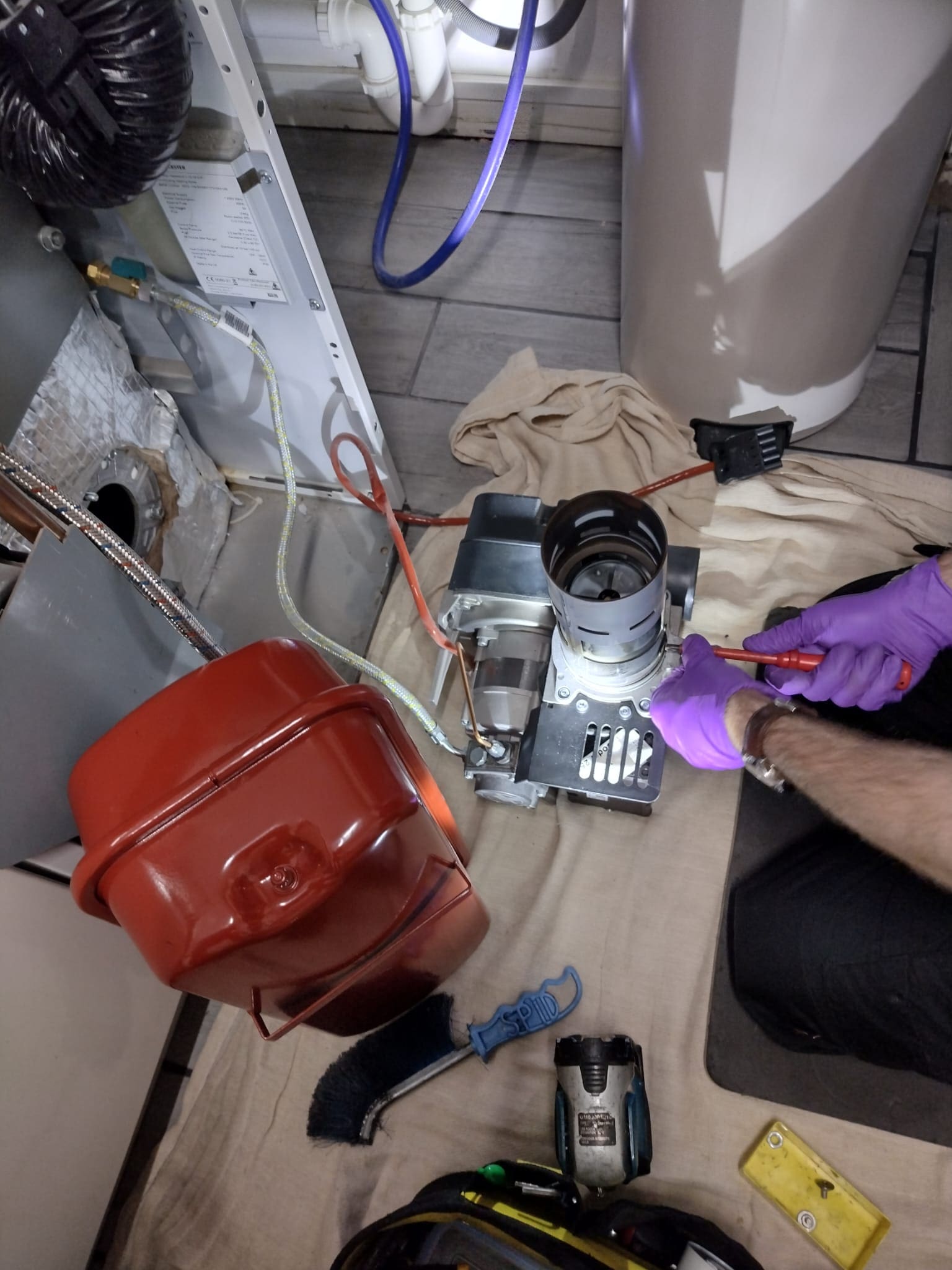 Boiler with exposed parts in kitchen with boiler engineer working