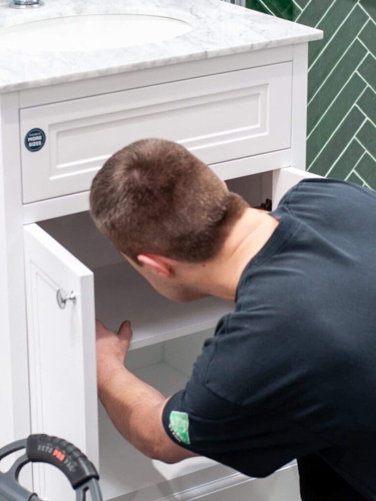 Man checking equipment beneath sink